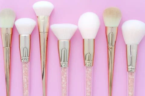 Set of makeup brushes on pink colored composed background. Top view point, flat Stock Photos