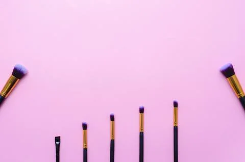 Set makeup brushes on pink colored background with copy space. Top view. Stock Photos