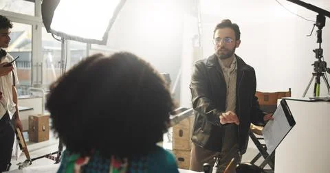 Set, man and director with script, talking and explaining scene to actor Stock Photos