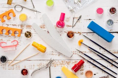 Set of manicure tools and nail polishes on a white wooden background. Stock Photos