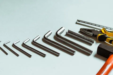 A set of metal hex keys next to a hammer, pliers and a tape measure. Stock Photos
