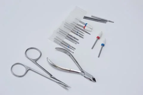 A set of metal tools for hardware manicure on a neutral white background. The Stock Photos