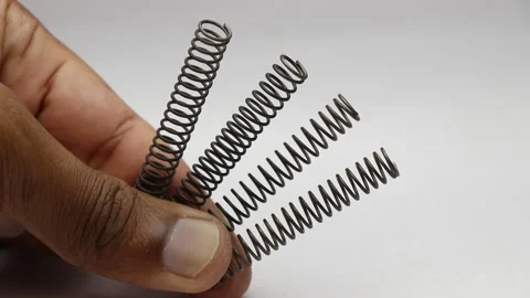 Set of metallic compression springs held in hand that is used to absorb shock Stock Footage 221347865