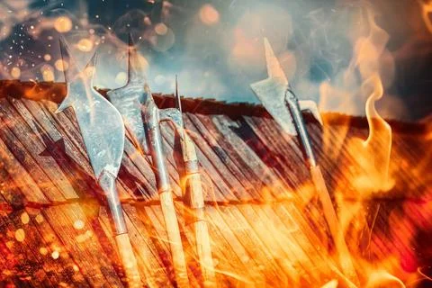 Set of middle age style weapons leaning on wooden roof. Fire effecct. Photos