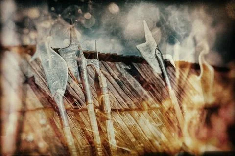 Set of middle age style weapons leaning on wooden roof. Fire effecct. Photos