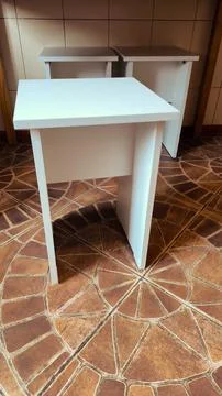 Set of modern white wooden stools on a patterned tiled floor Foto stock
