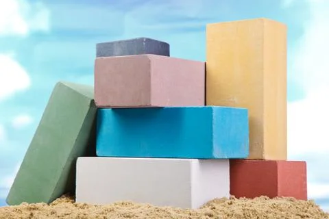 Set of multi-colored ceramic bricks on the sand at the blue sky background Stock Photos