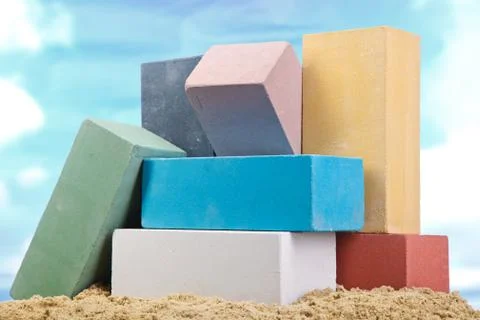 Set of multi-colored ceramic bricks on the sand at the blue sky background Stock Photos