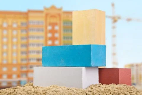 Set of multi-colored ceramic bricks on the sand at the building background wi Foto stock