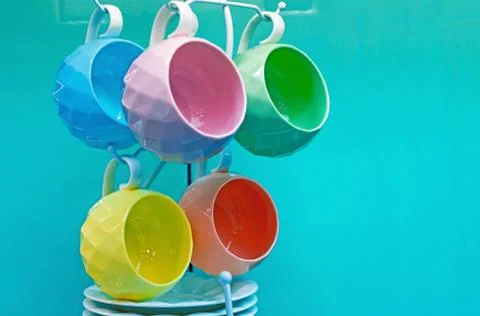 Set of multi-colored ceramic cups with saucers on a turquoise background. Stock Photos