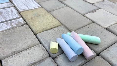 A set of multi-colored chalk lies on the paving stones next to the drawings Stock Footage 158552046