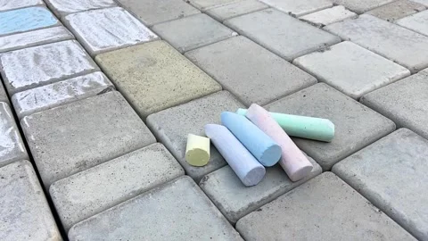A set of multi-colored chalk lies on the paving stones next to the drawings Stock Footage 158832166