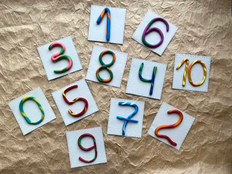 A set of multi-colored numbers made of plasticine, scattered randomly. Stock Photos