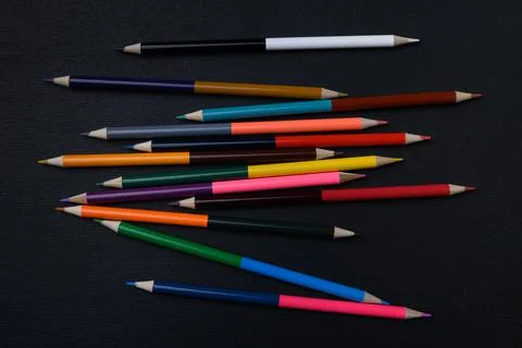 Set of multi-colored pencils scattered on a black table surface Stock Photos