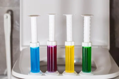A set of multi-colored syringes with different scents on the toilet bowl in the Photos
