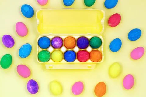 Set of multicolored easter eggs in yellow egg box on yellow background Stock Photos
