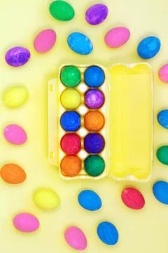 Set of multicolored easter eggs in yellow egg box on yellow background Stock Photos