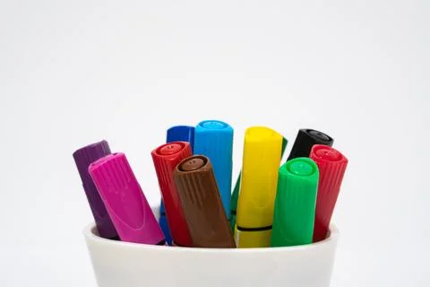 Set of multicolored markers in a white cup on a white background. Close-up. Stock Photos