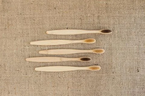 Set of natural bamboo toothbrushes on rustic burlap background Stock Photos