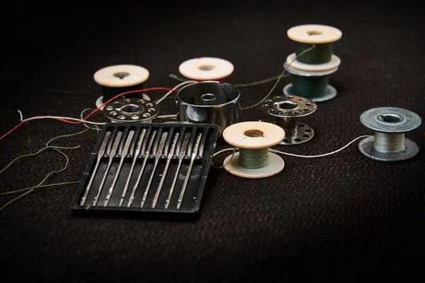 Set of needles and threads for a sewing machine on a dark background. Stock Photos