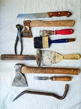 A set of old, worn out tools laid out on a white cloth. Stock Photos