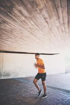 Set the pace then out-run yourself. a young man going for a run against an urban Stock Photos