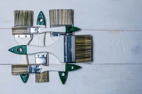 A set of paint brushes and a jar with white paint on a textured wood table .. Stock Photos