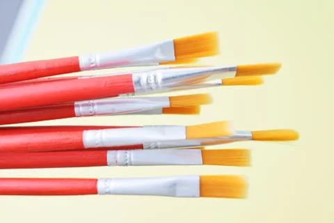 Set of paint brushes on yellow background Stock Photos