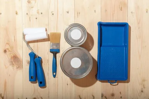 Set of paint rollers, brush, paint cans and blue tray neatly arranged on clea Stock Photos