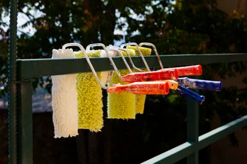 Set of paint rollers hanging out to dry over a fence Stock Photos