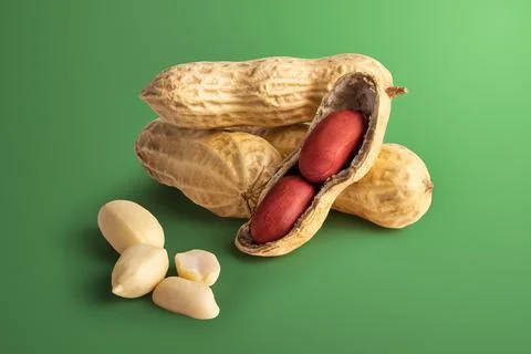 Set of peanuts in a nutshell, unpeeled and peeled peanuts on a green backgrou Stock Photos