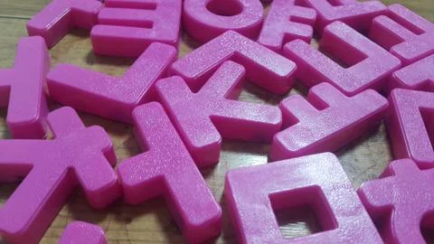 Set of plastic alphabet letters placed on a wooden floor Stock Photos