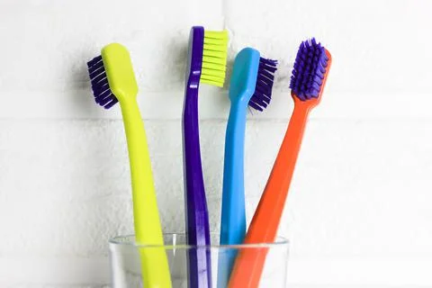 Set of plastic multicolored bright toothbrushes in a glass. Dental care Stock Photos