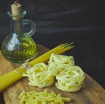 Set of raw pasta frame. Uncooked spaghetti, fusilli, fettuccine on a dark woo Stock Photos
