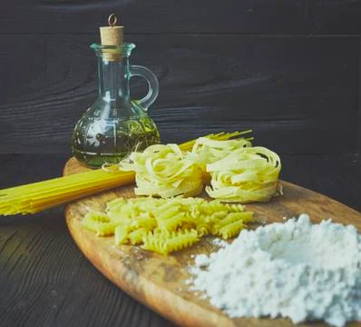 Set of raw pasta frame. Uncooked spaghetti, fusilli, fettuccine on a dark woo Stock Photos