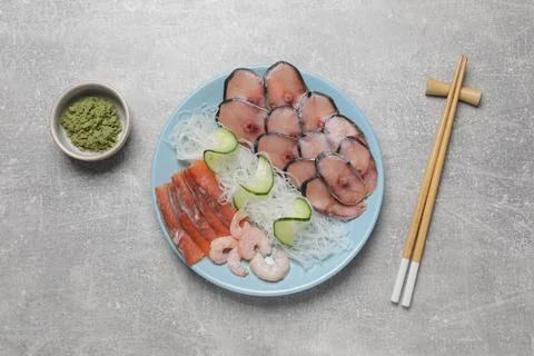 Set with raw salmon, mackerel slices, shrimps served with cucumber, funchos.. Stock Photos