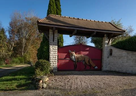 Set of red painted double gates wth a fox on them Stock Photos