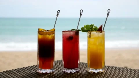 Set of Refreshing Fruit Cocktails Standing on Table on Beach near Turquoise Sea Stock Footage 156922687