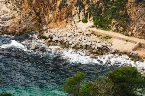 Set of rocks entering the sea with the waves breaking on the rocks. Stock Photos