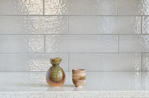 Set of sake cups and container on granite countertop against ceramic backspla Stock Photos