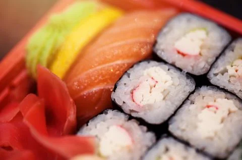 Set salmon rolls in a plastic plate on a black background Stock Photos