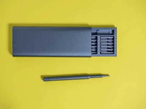 A set of screwdrivers with bits in a case on a yellow background. Tools for w Stock Photos