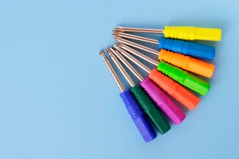 Set of screwdrivers with multi-colored handles on blue background. Fotos de archivo
