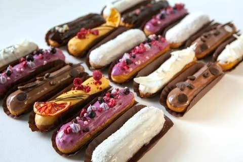 Set of several eclairs with various fillings and design isolate on a white ba Stock Photos