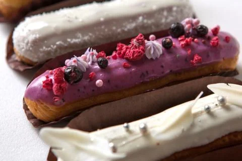 Set of several eclairs with various fillings and design isolate on a white ba Stock Photos