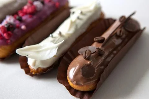 Set of several eclairs with various fillings and design isolate on a white ba Stock Photos