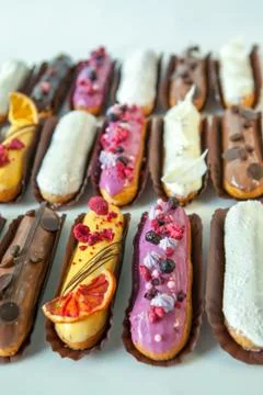 Set of several eclairs with various fillings and design isolate on a white ba Stock Photos
