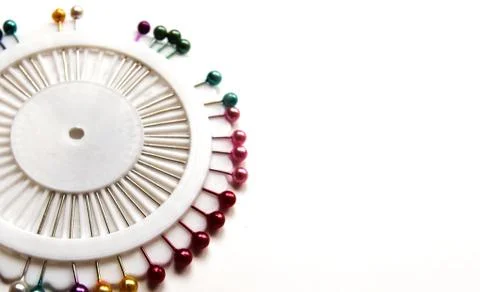 Set of sewing needles with colored beads in an organizer on a white bg. Stock Photos