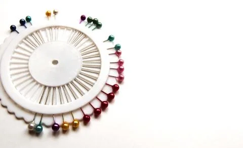 Set of sewing needles with colored beads in an organizer on a white bg. Stock Photos