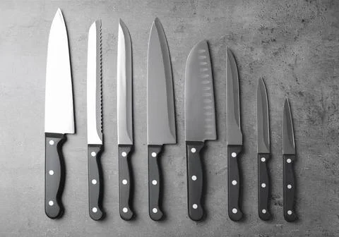 Set of sharp knives on grey background, flat lay Foto stock